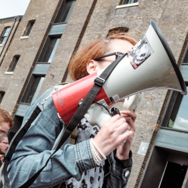 A woman in a denim jacket holding a red and white megaphone.